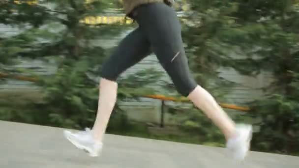Une athlète féminine court sur une allée asphaltée dans un parc
. - Séquence, vidéo