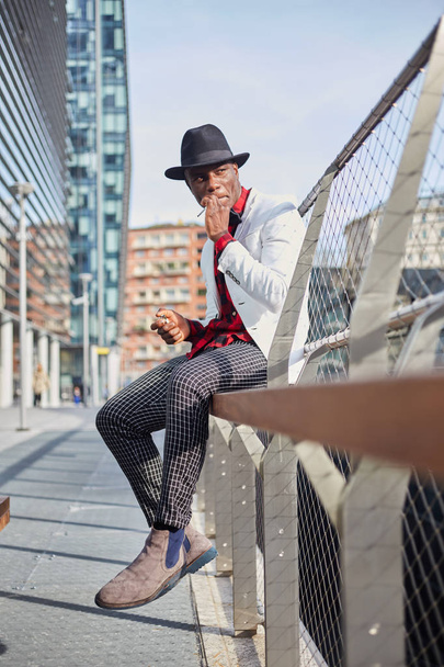 Fashion portrait of stylish young african man smoking cigarette - 写真・画像