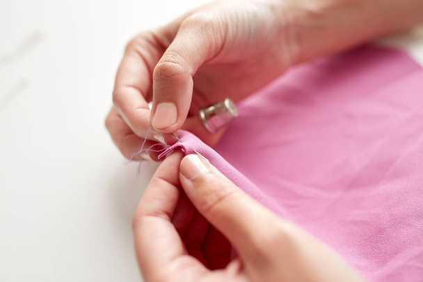 woman with needle stitching fabric pieces - Zdjęcie, obraz