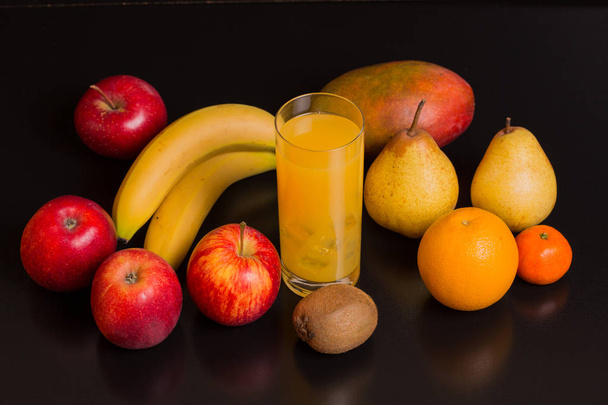 rozmaite owoce i sok pomarańczowy na czarnym tle, obraz studio  - Zdjęcie, obraz