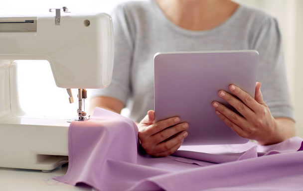 tailor with sewing machine, tablet pc and fabric - Фото, изображение