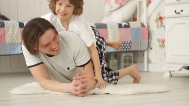 Son and his young father are playing on the floor in the bedroom. - Filmmaterial, Video