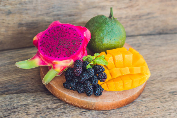 Sliced dragon fruit and mango on an old wooden background - Photo, Image