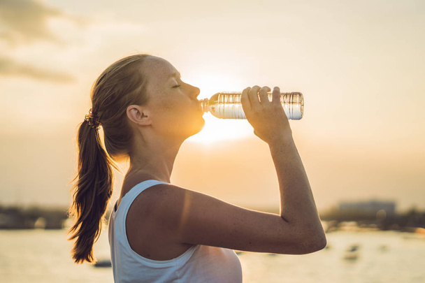 Sporty woman drinking water outdoor on sunny day - Photo, image