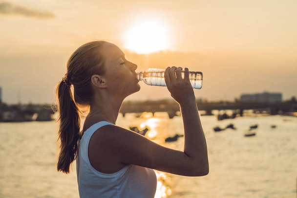 Sporty woman drinking water outdoor on sunny day - Фото, зображення