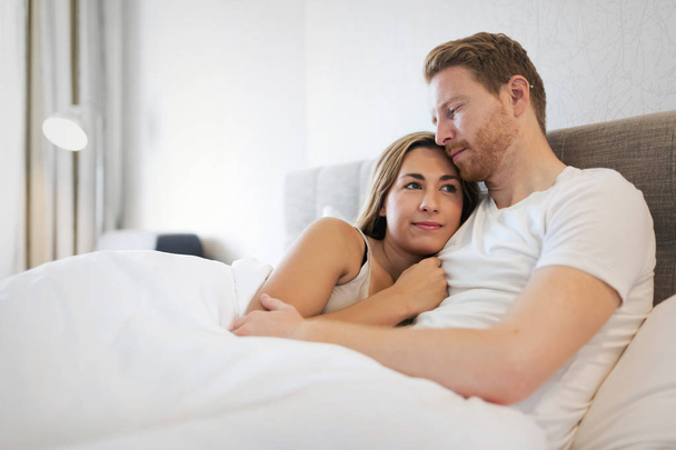 Beautiful couple lying in bed in morning - Фото, изображение