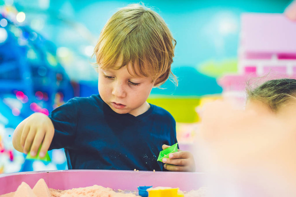 Boy playing with kinetic sand in preschool. The development of fine motor concept. Creativity Game concept - Photo, image