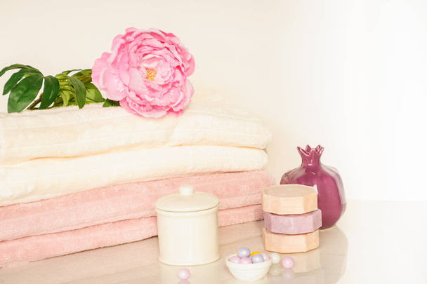 Bath setting in white and pink colors. Towel, aroma oil, flowers, soap. Selective focus, horizontal. - Photo, image