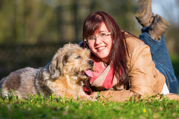 young woman lies with her dog in the grass - Foto, Bild
