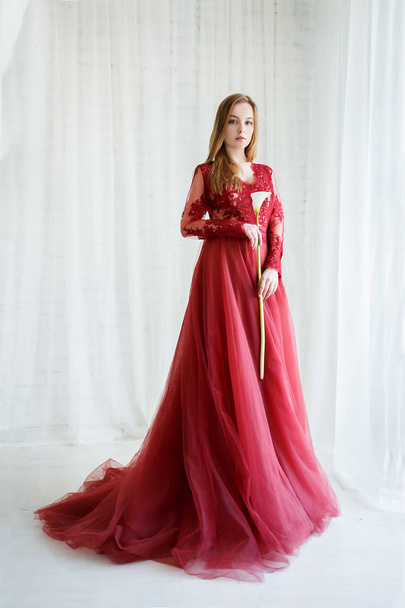 bride in an red gown with calla flower in hands - Фото, изображение