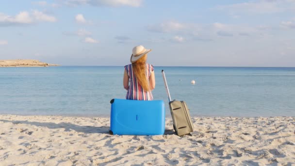 Fiatal nő ül a strandon egy bőrönddel - Felvétel, videó