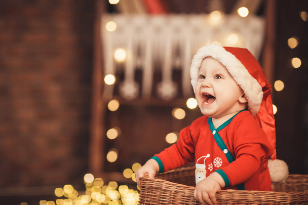 Petit garçon au chapeau de Père Noël assis dans un panier en osier
 - Photo, image