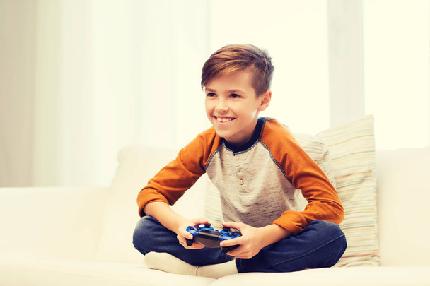 happy boy with joystick playing video game at home - Foto, afbeelding
