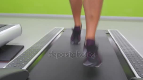 Jambes féminines jogging et course sur tapis roulant dans la salle de gym. Jeune femme faisant de l'exercice pendant l'entraînement cardio. Pieds de filles en chaussures de sport s'entraînant à l'intérieur au club de sport. Gros plan
 - Séquence, vidéo