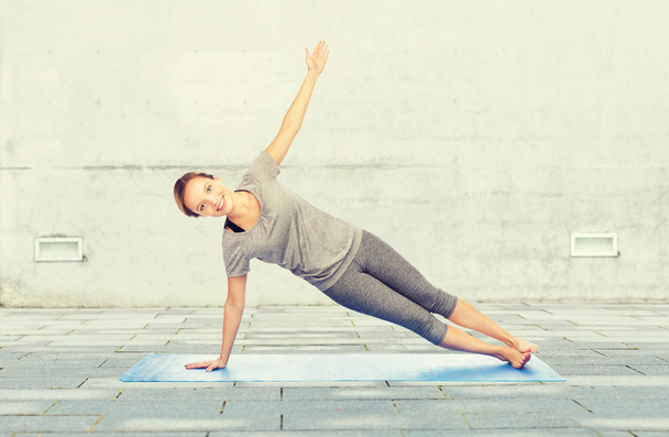 woman making yoga in side plank pose on mat - Foto, Imagem