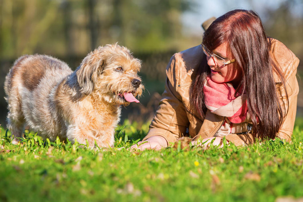 joven mujer se acuesta con su perro en la hierba
 - Foto, Imagen