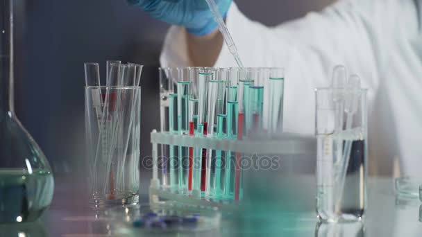 Laboratory scientist conducting tests by adding drop of reagent to mixture - Кадри, відео