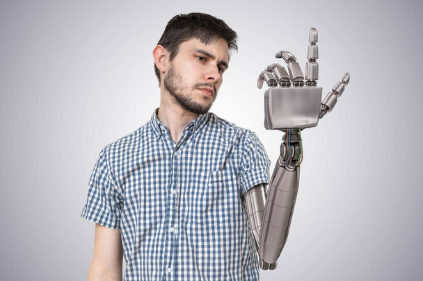 若い男は、彼の手の代替としてロボットのハンドを持ってください。手の 3 d レンダリングされたイラストレーション. - 写真・画像