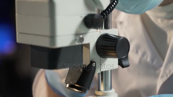 Laboratory worker examining abnormal structure of cells under microscope - Imágenes, Vídeo