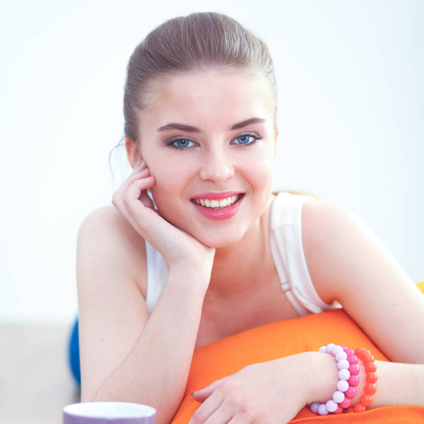 Smiling young woman lying on a white floor with pillow - Photo, image