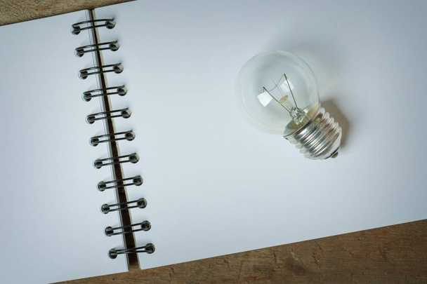 Een lampje geplaatst op een geopende schetsboek - Foto, afbeelding