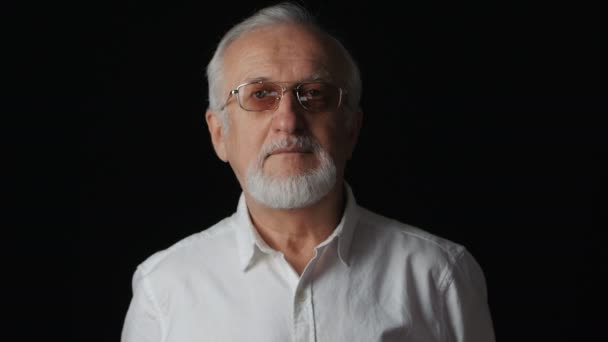 Primer plano retrato de un hombre mayor con una camisa blanca sobre fondo negro
 - Metraje, vídeo
