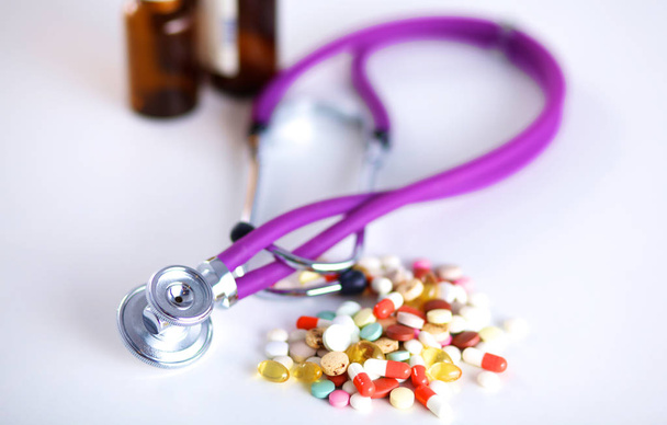 Gros plan des pilules réparties sur la table avec stéthoscope et cœur couché à côté
 - Photo, image