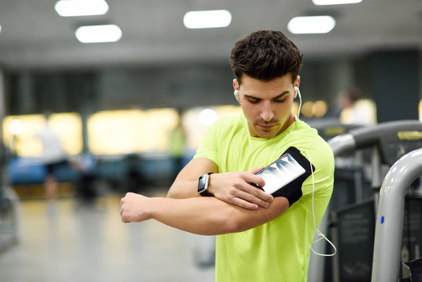 Jeune homme utilisant un smartphone debout dans la salle de gym
 - Photo, image