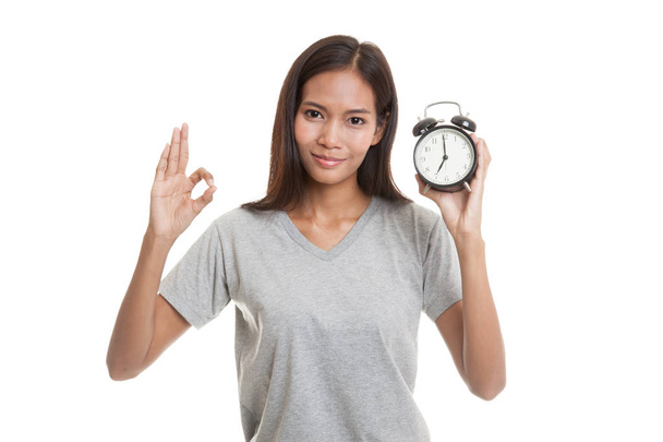 Young Asian woman show OK with a clock. - Zdjęcie, obraz