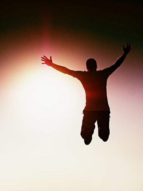 Jumping man. Gek jongeman is springen op rood hemelachtergrond. Silhouet van jumping man en mooie zonsondergang hemel. Ontwerp-element. Vintage effect. - Foto, afbeelding