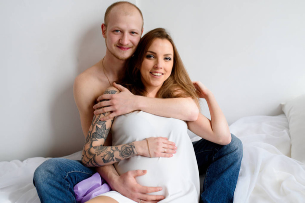 Beautiful couple in anticipation of a child, lie in bed. - 写真・画像