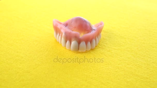 closeup of teeth denture on rotating yellow plate - Filmati, video