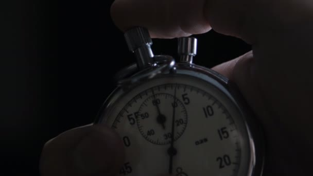 One person starting up a stopwatch at black background - Footage, Video