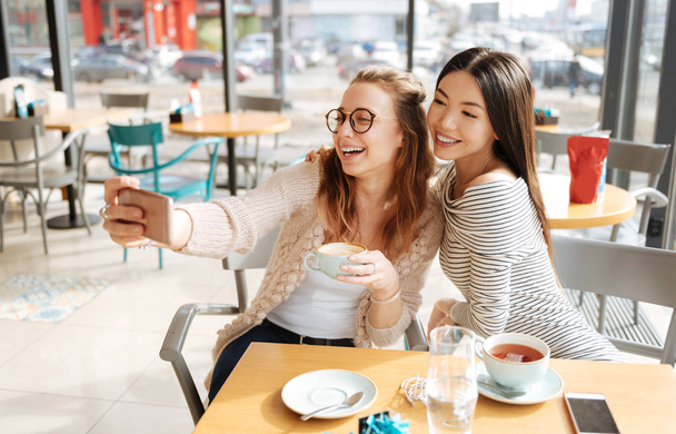 Two girlfriends doing selfie at cafe - Fotoğraf, Görsel