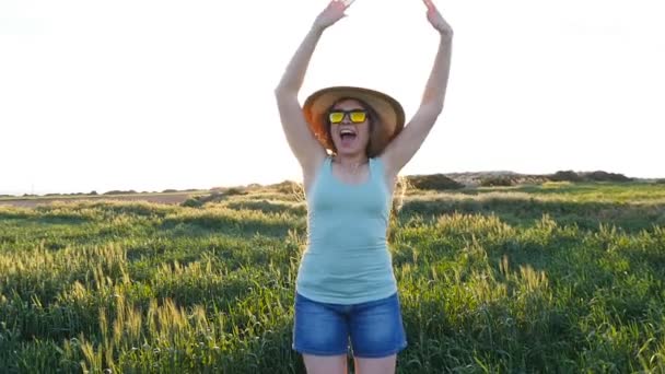 glückliche junge Frau mit Hut genießt den Sommer auf der grünen Wiese bei Sonnenuntergang - Filmmaterial, Video