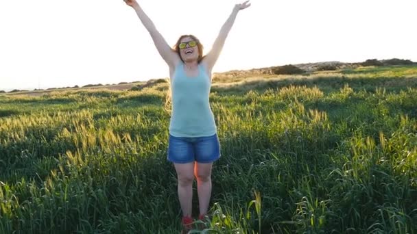 Happy young woman in hat enjoying summer in green field at sunset - Footage, Video