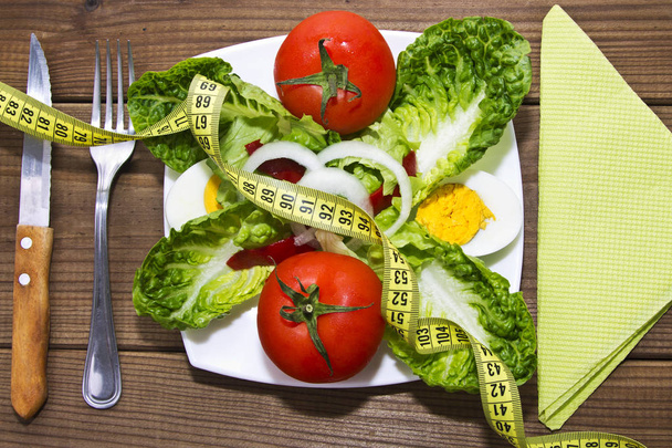 Salad plate and tape measure on wood - Foto, imagen