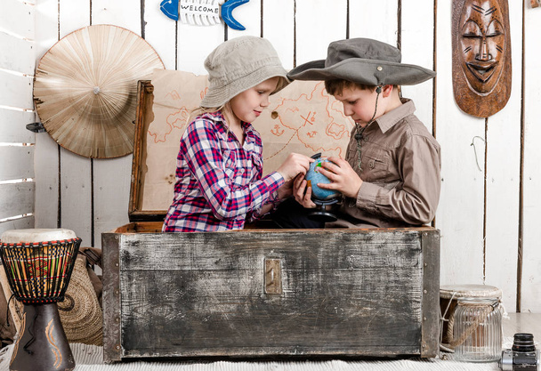 little boy and girl study globe in big chest - Foto, afbeelding