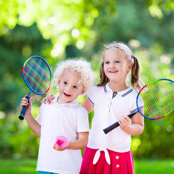 子供たちがバドミントンや屋外コートでテニスをプレイします。 - 写真・画像