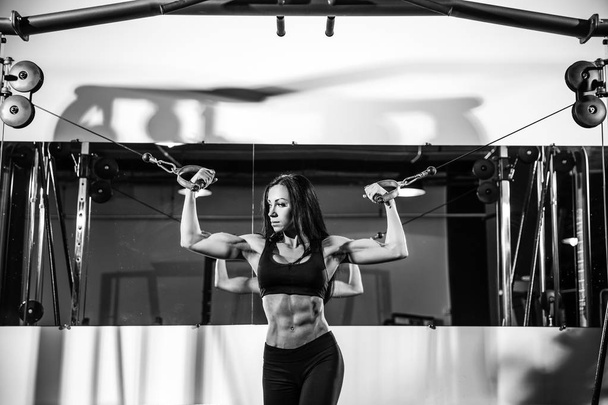 woman flexing muscles on cable machine in gym. exercise on biceps - Foto, Imagen