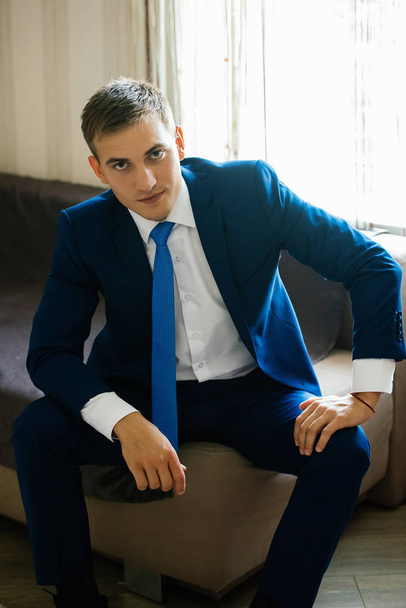 A man in a suit is sitting on the sofa. Man portrait. Businessma - Фото, изображение