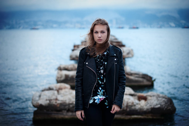 A sad young girl is standing on the sea dock - Foto, imagen