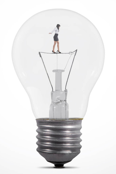 Businesswoman balancing inside lamp - Valokuva, kuva
