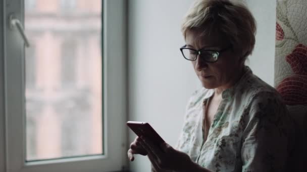 Nainen katselee jotain älypuhelimen näytöllä
 - Materiaali, video