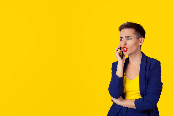 Angry frustrated woman talking on phone looking to copy space isolated yellow background wall. Negative human emotion, face expression - 写真・画像