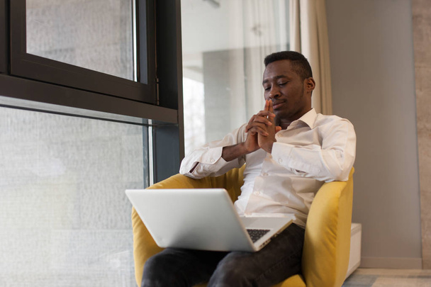 Young african-american businessman is working on his laptop in o - 写真・画像