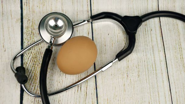stetoskop a vejce na dřevěné pozadí - Fotografie, Obrázek