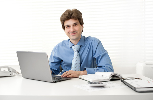 Деловой человек улыбается во время работы в офисе
 - Фото, изображение