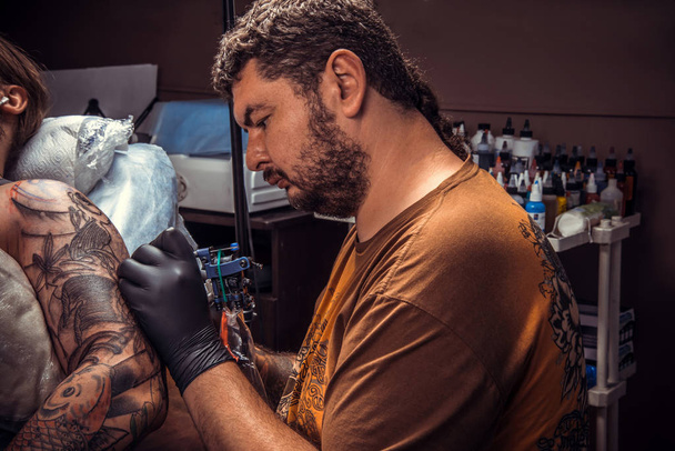 Специалист по татуировкам делает татуировки в студии
 - Фото, изображение