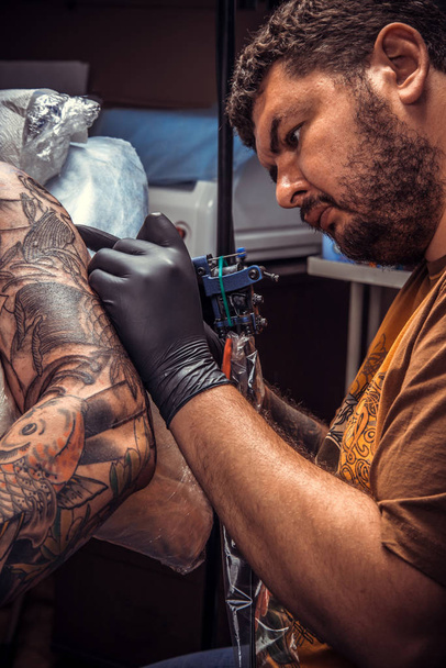 Professionele tattooer works in tatoeage studio - Foto, afbeelding